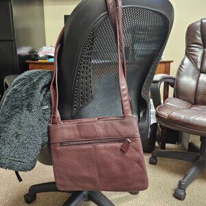 Burgundy/brown purse with snap button to close and zippered compartments